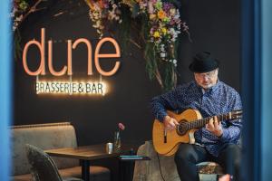ミエルノにあるDune Beach Resort - Cのレストランでギターを弾く男