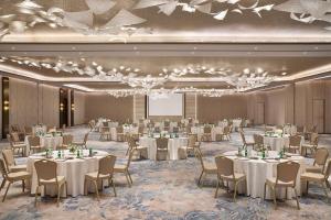 a banquet hall with white tables and chairs and a screen at The St. Regis Riyadh in Riyadh +104 photos