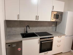 a kitchen with white cabinets and a sink and a microwave at Borstel - Alte Schmiede in Borstel