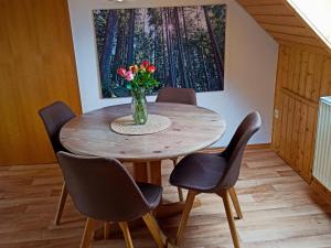 a table with chairs and a vase of flowers on it at Ferienwohnung Brentenholz in Sankt Georgen im Schwarzwald