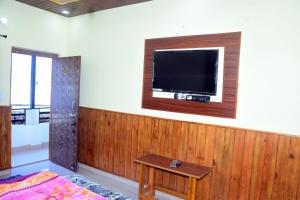 Habitación con TV de pantalla plana en la pared en Kaafal hotel & restaurant, en Dhanaulti