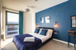 een blauwe slaapkamer met een bed met een blauwe muur bij Morden 2 Bed Apartment - Manchester Old Trafford in Manchester