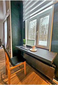 a desk with a laptop and a chair next to a window at AMRAI Rīga in Rīga