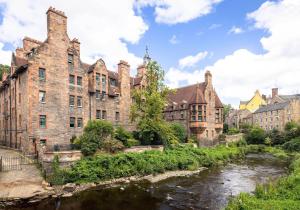 an old castle with a river in front of it at The Well Court Residence in Edinburgh