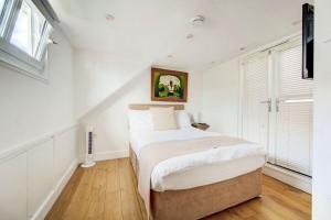 - une chambre blanche avec un grand lit et des fenêtres dans l'établissement Dovehouse, à Londres