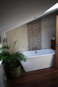 La salle de bains est pourvue d'une baignoire blanche et d'une plante. dans l'établissement Unique 5 bed home Amazing Valley views & Hot tub, à Bampton
