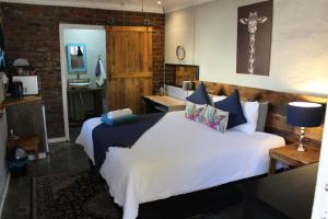 1 dormitorio con 1 cama grande y baño en The Hancock Inn, en Klerksdorp