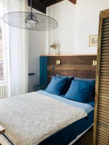 a bedroom with a large bed with blue pillows at La bohème place aux herbes in Uzès