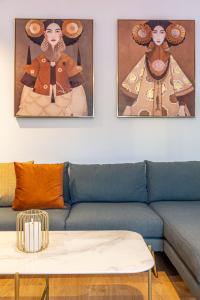 a living room with a blue couch and two paintings at Efrosini Apartments in Heraklio