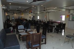 a restaurant with people sitting at tables and chairs at Hotel Rudra in Dehradun