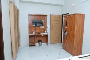 Habitación con escritorio, TV y puerta. en Hotel Rudra en Dehradun