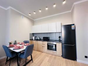 a kitchen with a table and a black refrigerator at Уютный уголок в центре города Grand Turan in Taldykolʼ