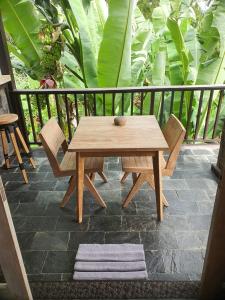 a wooden table and chairs on a patio with plants at Widya Luxury House in Ubud