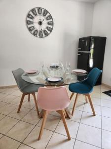 a dining room table with chairs and a clock on the wall at Maison cosy et décorée avec goût à la campagne in Sévérac +8 photos