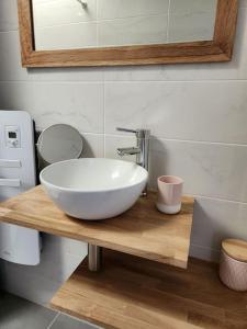 a bathroom with a white bowl sink on a wooden counter at Maison cosy et décorée avec goût à la campagne in Sévérac