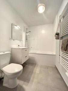 a white bathroom with a toilet and a sink and a tub at Appartement le peuplier proche de la plage. in Bray-Dunes