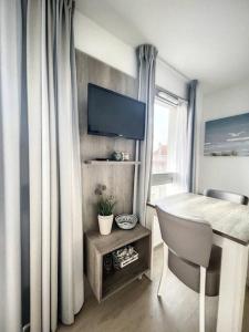 a room with a desk with a chair and a television at Appartement le peuplier proche de la plage. in Bray-Dunes