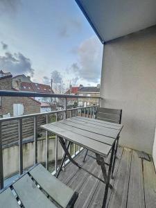 a wooden deck with a table and a bench on a balcony at Appartement le peuplier proche de la plage. in Bray-Dunes