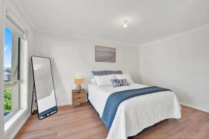 a white bedroom with a bed and a mirror at Tranquil Escape by Ready Set Stay in Dromana +7 photos
