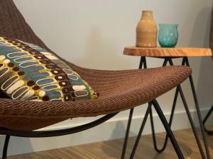 a rattan chair with a pillow on it next to a table at Hotel Au Nom De Dieu in Dilsen-Stokkem