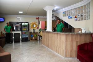 two men standing at a bar in a restaurant at Hotel Casa Nova in Várzea Grande