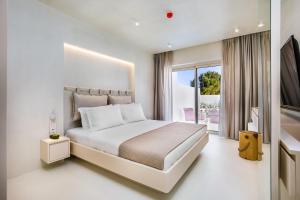 a white bedroom with a large bed and a balcony at Cocoοns Suites & Villas Fourka in Fourka