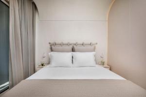 a white bed with white pillows in a bedroom at Cocoοns Suites & Villas Fourka in Fourka