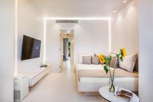 a white living room with a couch and a tv at Cocoοns Suites & Villas Fourka in Fourka