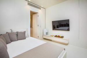 a white bedroom with a bed and a flat screen tv at Cocoοns Suites & Villas Fourka in Fourka