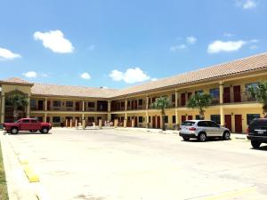 a large building with cars parked in a parking lot at Boca Chica Inn and Suites in Brownsville