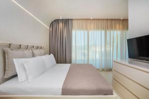 a bedroom with a white bed and a television at Cocoοns Suites & Villas Fourka in Fourka
