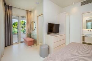 a white bedroom with a tv and a bed at Cocoοns Suites & Villas Fourka in Fourka