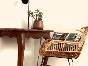 una sedia di vimini seduta accanto a un tavolo di legno con una pianta di Hotel Au Nom De Dieu a Dilsen-Stokkem
