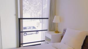 Un dormitorio con una cama y una ventana con un coche al aire libre en Niseko White Villas1, en Niseko