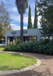 a building with a palm tree in front of it at St Eve Lodge & Spa in Bloemfontein