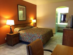 a hotel room with a bed and a table with a chair at Boca Chica Inn and Suites in Brownsville
