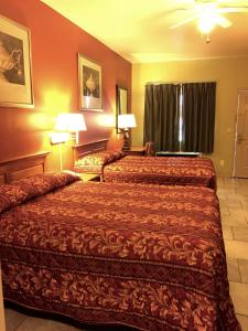 two beds in a hotel room with red walls at Boca Chica Inn and Suites in Brownsville