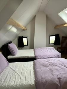 a attic room with two beds and a chair at De Danser 2 in Klaaswaal