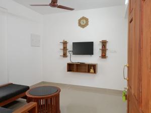 a living room with a tv on a white wall at Alite Enclaves Fully furnished apartments in Trichūr
