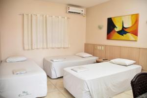 a room with two beds and a painting on the wall at Hotel Casa Nova in Várzea Grande