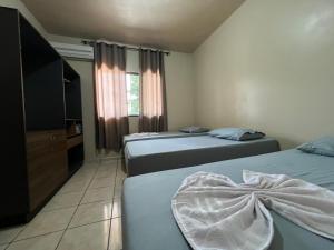 a hotel room with two beds and a television at Apartamento aconchegante no centro de Toledo in Toledo
