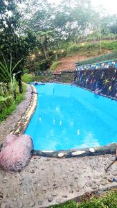 uma grande piscina azul de água no lado de uma colina em Villa Situ Jampang Campsite em Megamendung