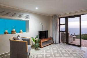 een woonkamer met een tv en een groot raam bij Pezula Beachfront Splendour - 5 bedroom in Knysna