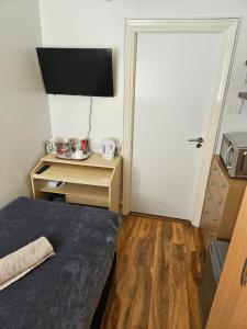 Cette chambre comprend un lit et un bureau avec une télévision. dans l'établissement Comfortable single room in Family home, Heathrow airport, à Northolt
