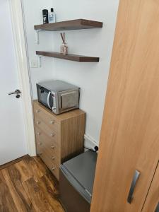 Cette chambre comprend un four micro-ondes au-dessus d'une commode. dans l'établissement Comfortable single room in Family home, Heathrow airport, à Northolt