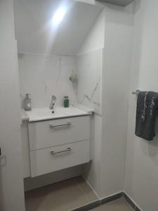 a white bathroom with a sink and a mirror at HÉBERGEMENT au LOGIS in Sougé-le-Ganelon