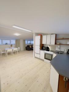 a kitchen and living room with white cabinets and a table at aday - Holiday Apartment in the heart of Frederikshavn in Frederikshavn