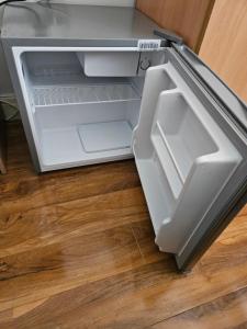 an open refrigerator with its door open on the floor at Comfortable single room in Family home, Heathrow airport in Northolt