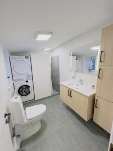 a bathroom with a toilet and a washing machine at aday - Holiday Apartment in the heart of Frederikshavn in Frederikshavn