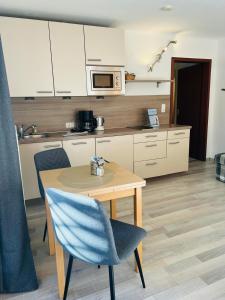 eine Küche mit einem Holztisch und einem blauen Stuhl in der Unterkunft StrandLiebeDuhnen in Cuxhaven